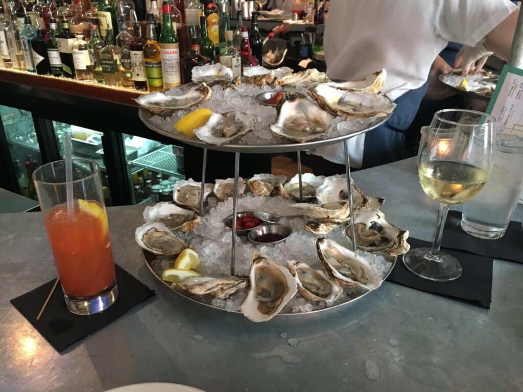 Plate of oysters and two drinks on a bar at the Franklin. - top restaurant to visit in Portsmouth New Hampshire