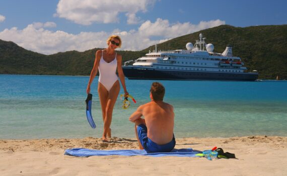man and woman on a beach in front of a small cruise ship