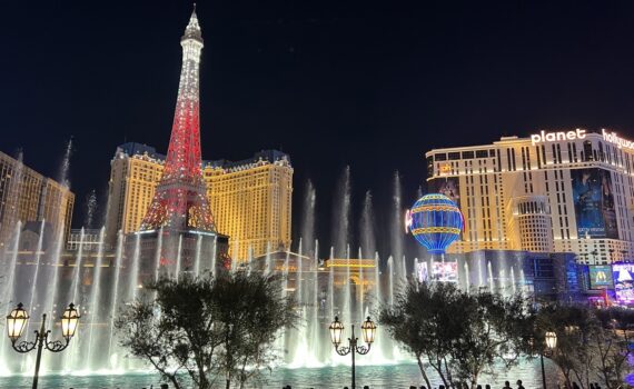 Fountains, with the Las Vegas Paris hotel in the background lit up at night.