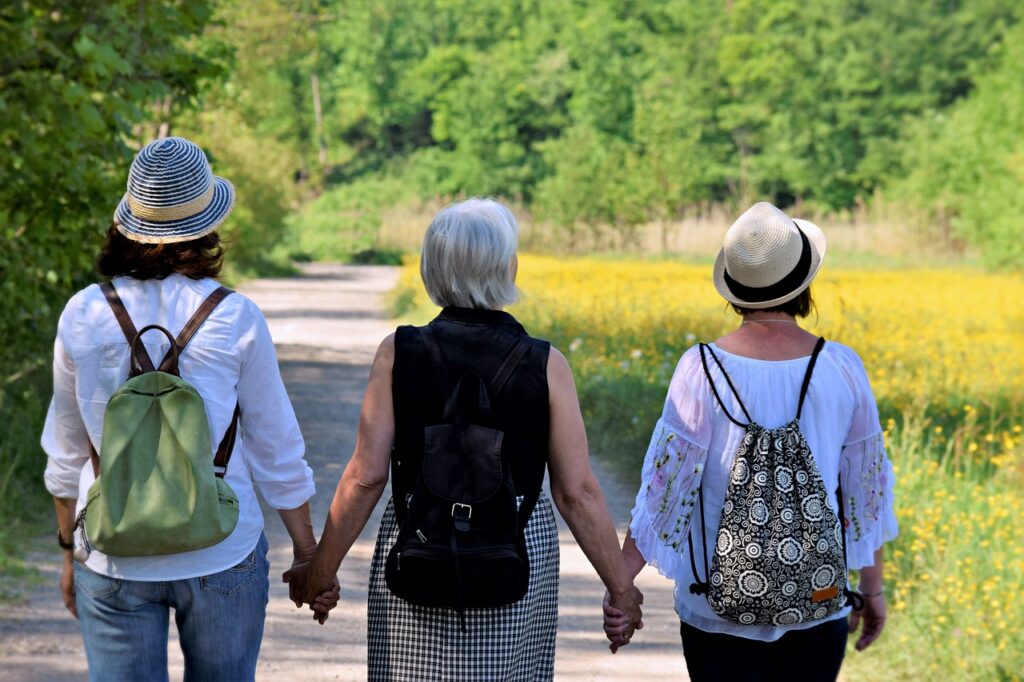 Three women travelers with back packs holding hands