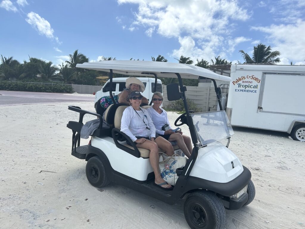 Women navigating the beaches of Bimini by golf cart
