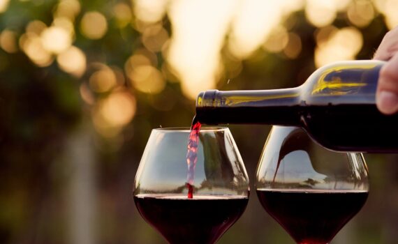 Red wine being poured into wine glasses at sunset. Romantic getaway.