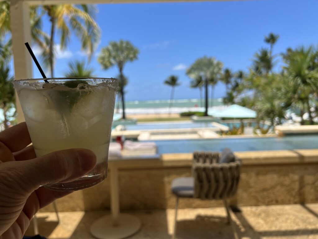 A drink held in front of a view of the ocean in Puerto Rico