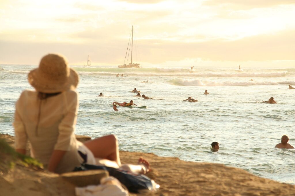 Woman sitting on a beach in hawaii looking at the ocean