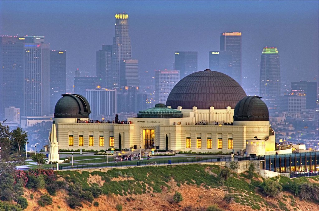 Griffith Observatory lit up at night with the sky line of Los Angeles behind it