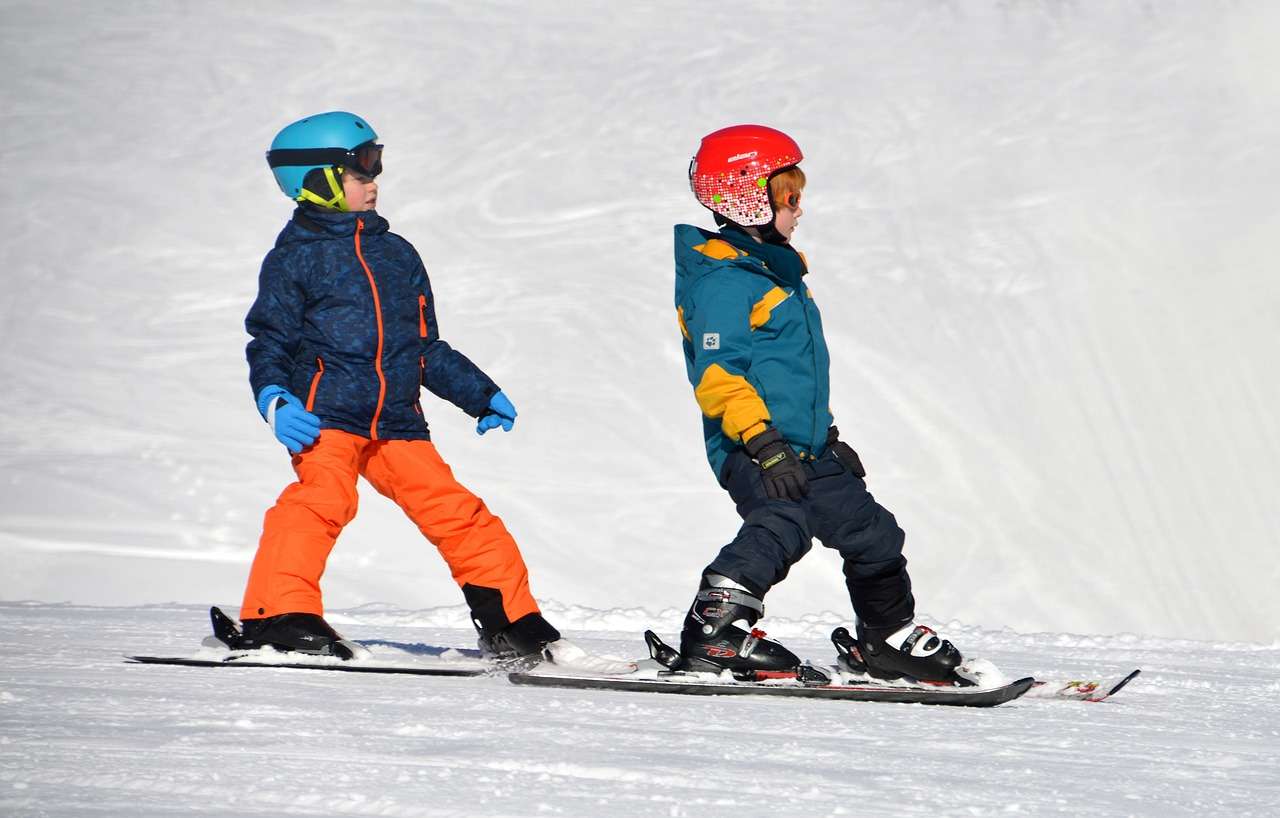 Two children with helmets on taking ski lessons