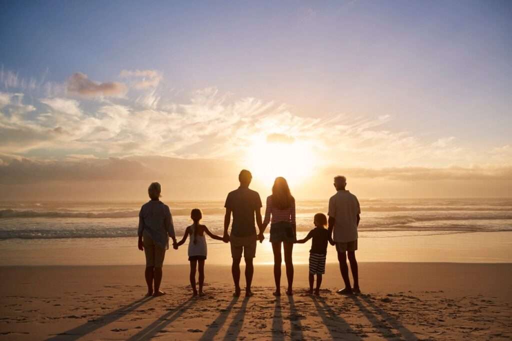A family of 6 holding hands watching the sun set over the ocean