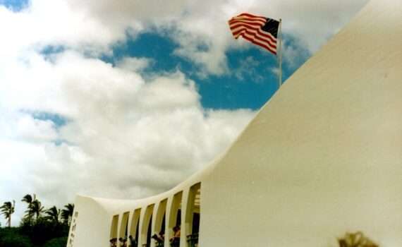 Memorial at Pearl Harbor with American Flag flying against a blue sky with clouds