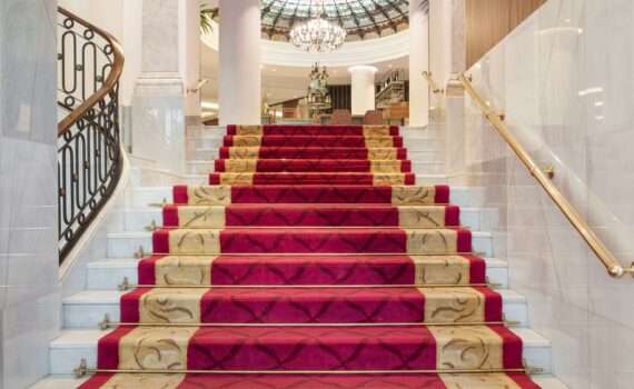 The grand stairs to the lobby of the Hotel Colon, a Gran Melia Property. Stairs are covered in a royal red carpet with gold trim.