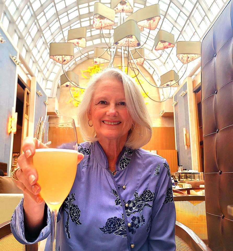 Debbie holding a cocktail at the High Tea at the Ritz-Carlton in Singapore