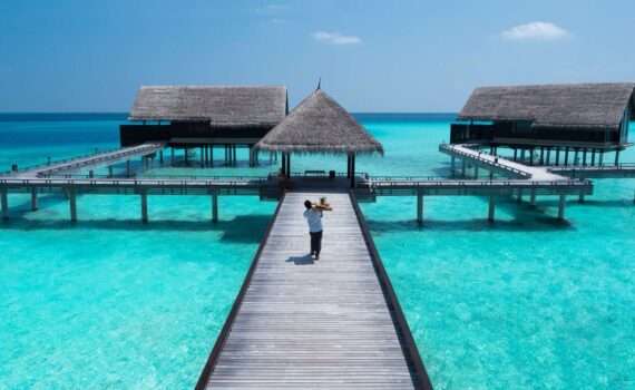 A pier going out over the clear blue ocean in the Maldives to overwater bungalows. One&Only Reethi Rah - a luxury hotel