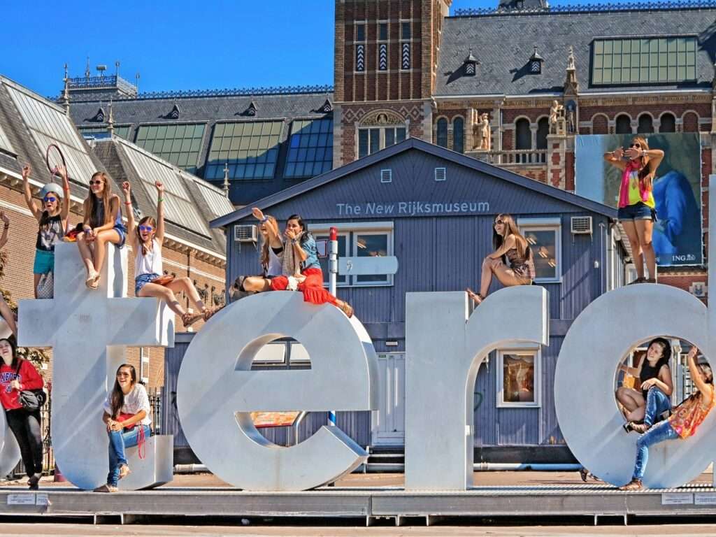 Woman and Girls climbing on the IAMAMSTERDAM Sign in front of the Rijksmuseum in Amsterdam.