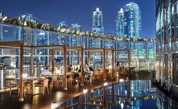 Armani Amal Terrace - view of the out door cafe at night with the city skyline behind the diners