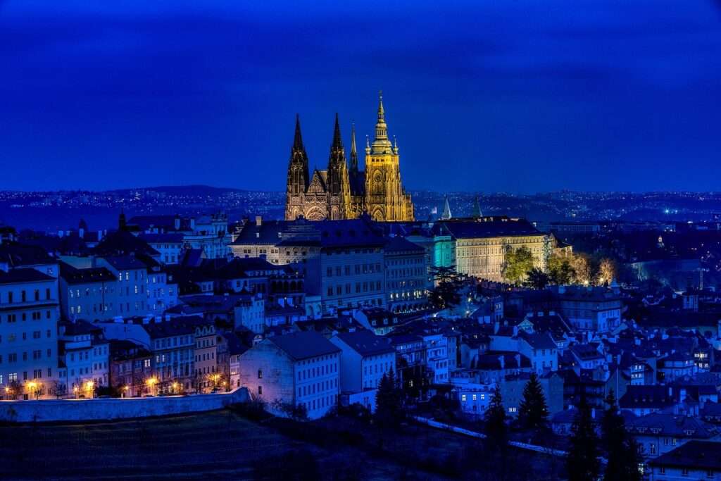 Aerial view of Prague lit up at night with the cathedral