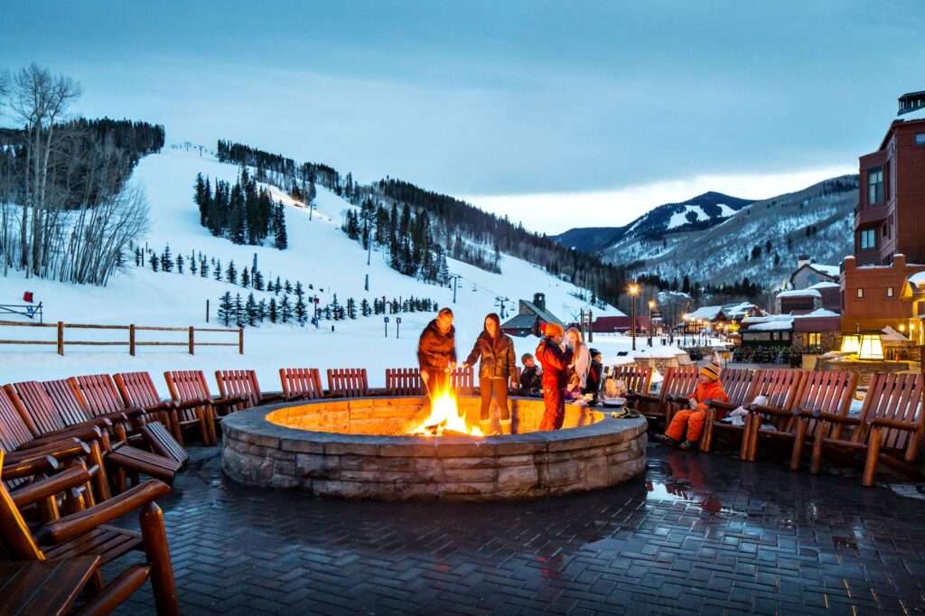 Family roasting marshmallows outside over a fire at Park Hyatt Beaver Creek