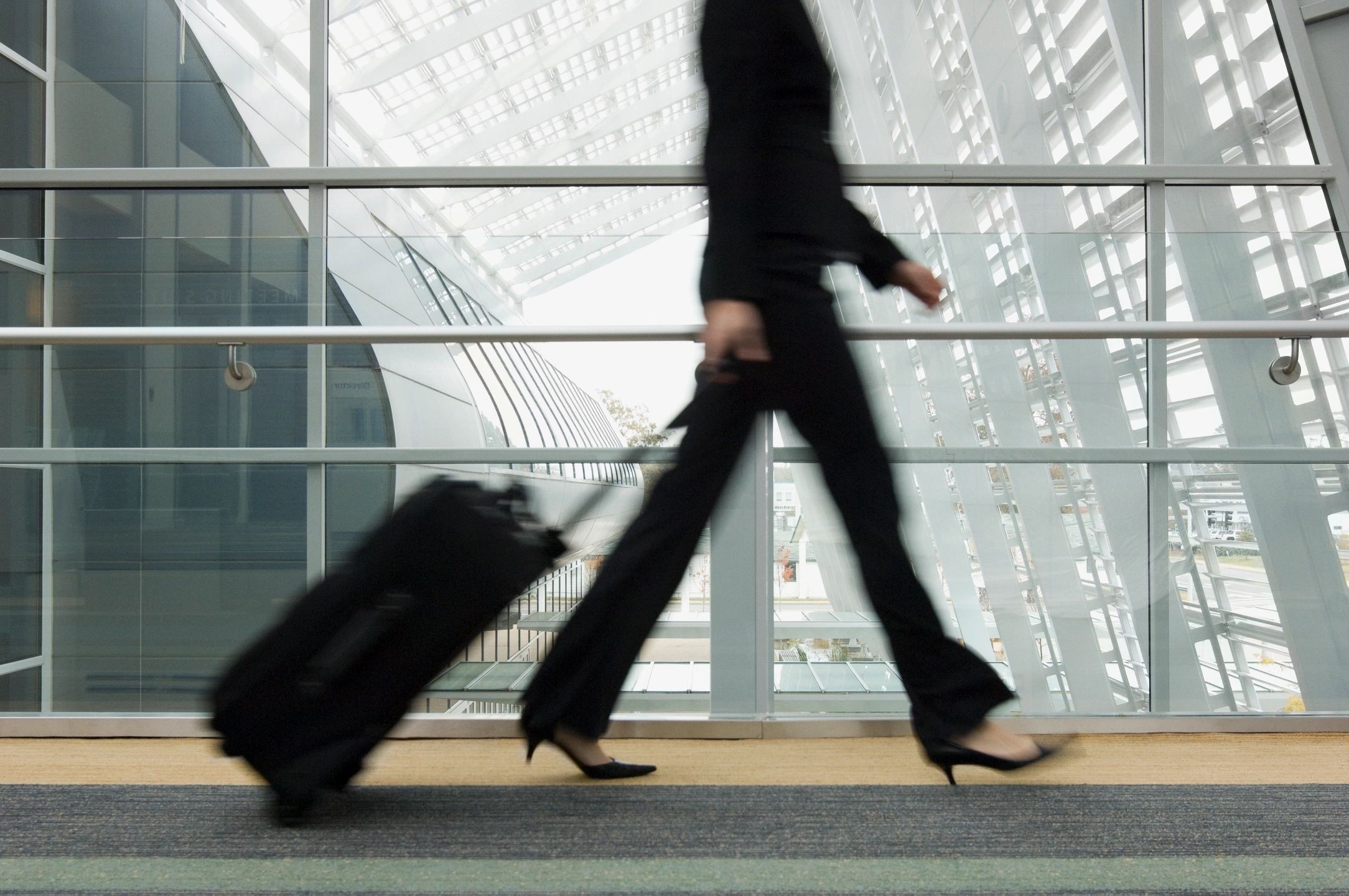 Woman walking through the airport with a small carry on bag